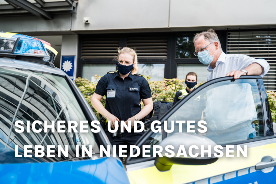 Stephan Weil neben einem Polizeiauto